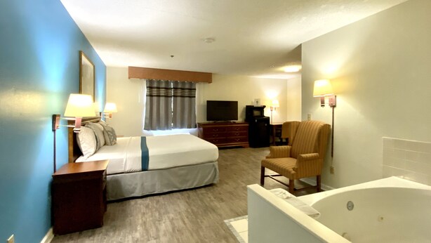 A hotel room with a bed, a chair, a TV, a desk, and a bathtub. - FairBridge Inn Express Mount Vernon (Mount Vernon)