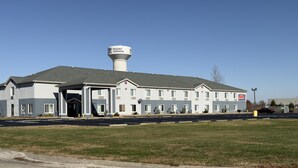 A multi-story hotel with a prominent water tower, a parking lot, and a sign for a nearby restaurant. - FairBridge Inn Express Mount Vernon (Mount Vernon)