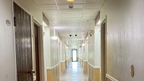 A long, narrow hallway with a tiled floor, doors on both sides, and a light source at the end. - FairBridge Inn Express Mount Vernon (Mount Vernon)