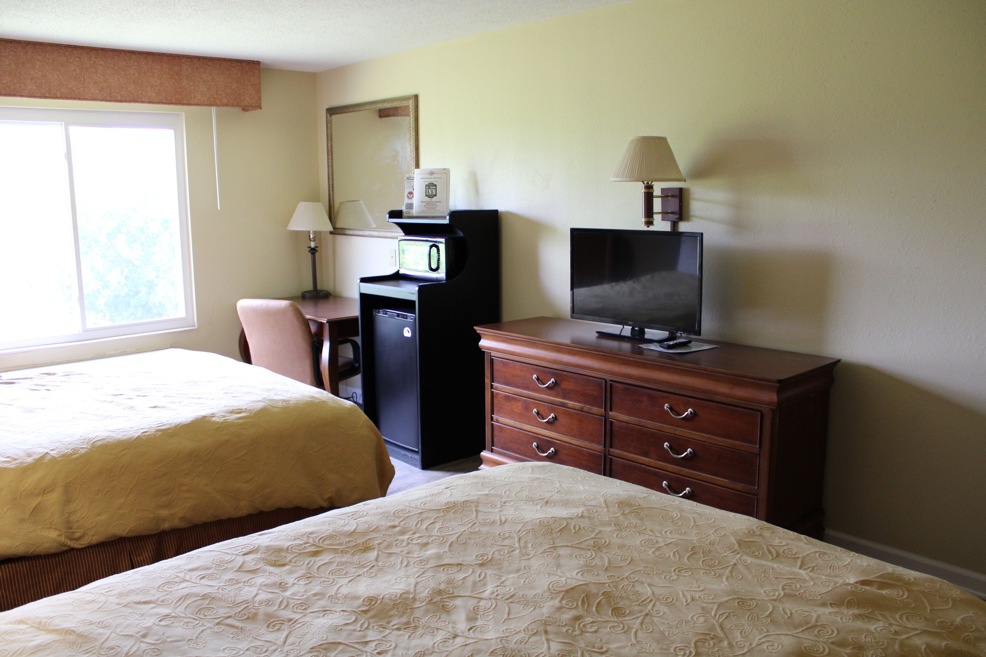 A hotel room with two beds, a desk with a computer, a television, and a dresser.