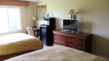 A hotel room with two beds, a desk with a computer, a television, and a dresser.