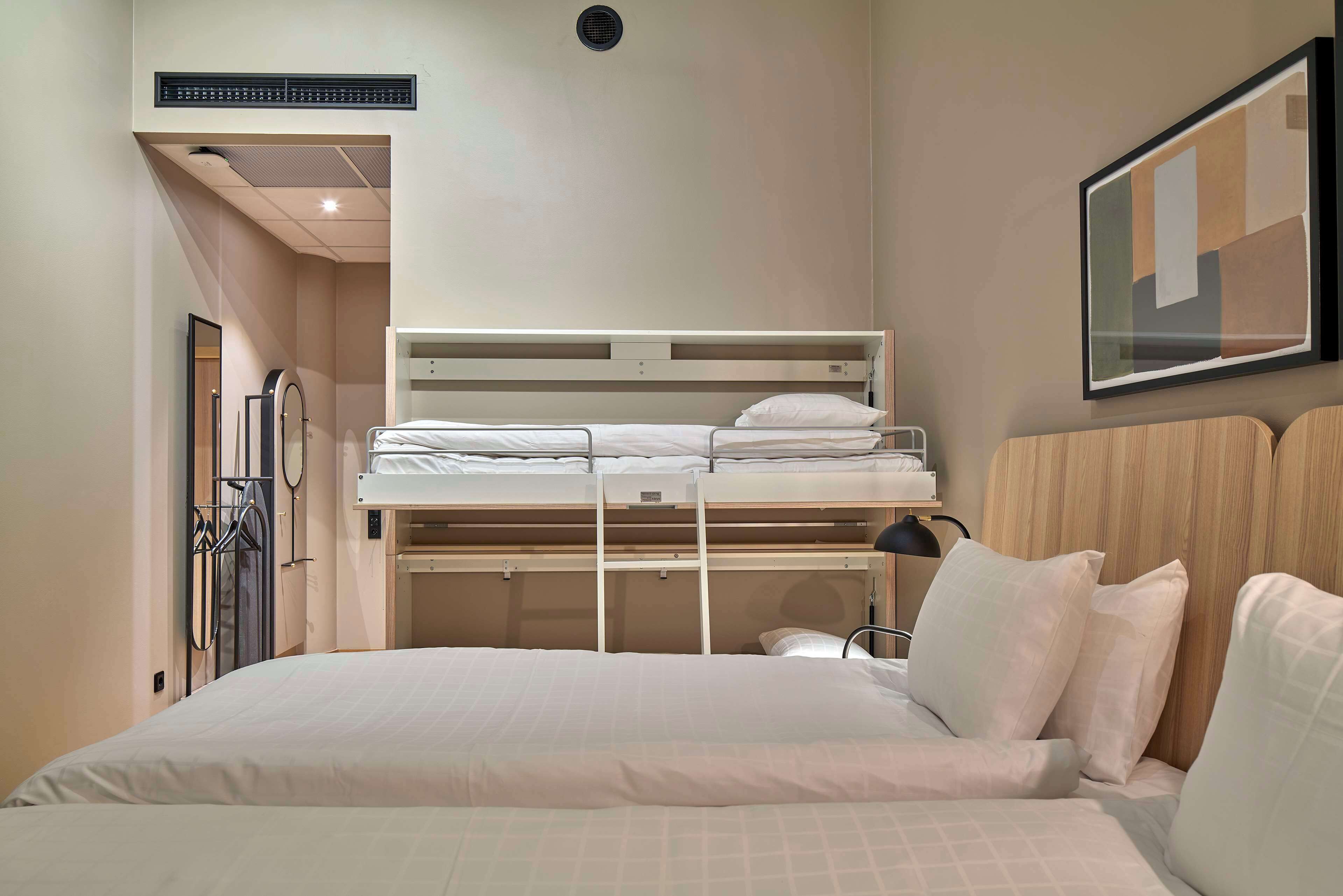 A hotel room with a bunk bed, a desk, and a chair.