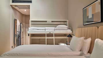 A hotel room with a bunk bed, a desk, and a chair.