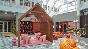 Un interior moderno con estructura de madera que recuerda a una casa, asientos rosados y un letrero que dice 'COAST'.