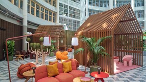 Un espacio interior moderno con una zona de estar central, una estructura de madera y diversas plantas.