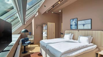 A modern hotel room with a large bed, a desk, a chair, and a TV.