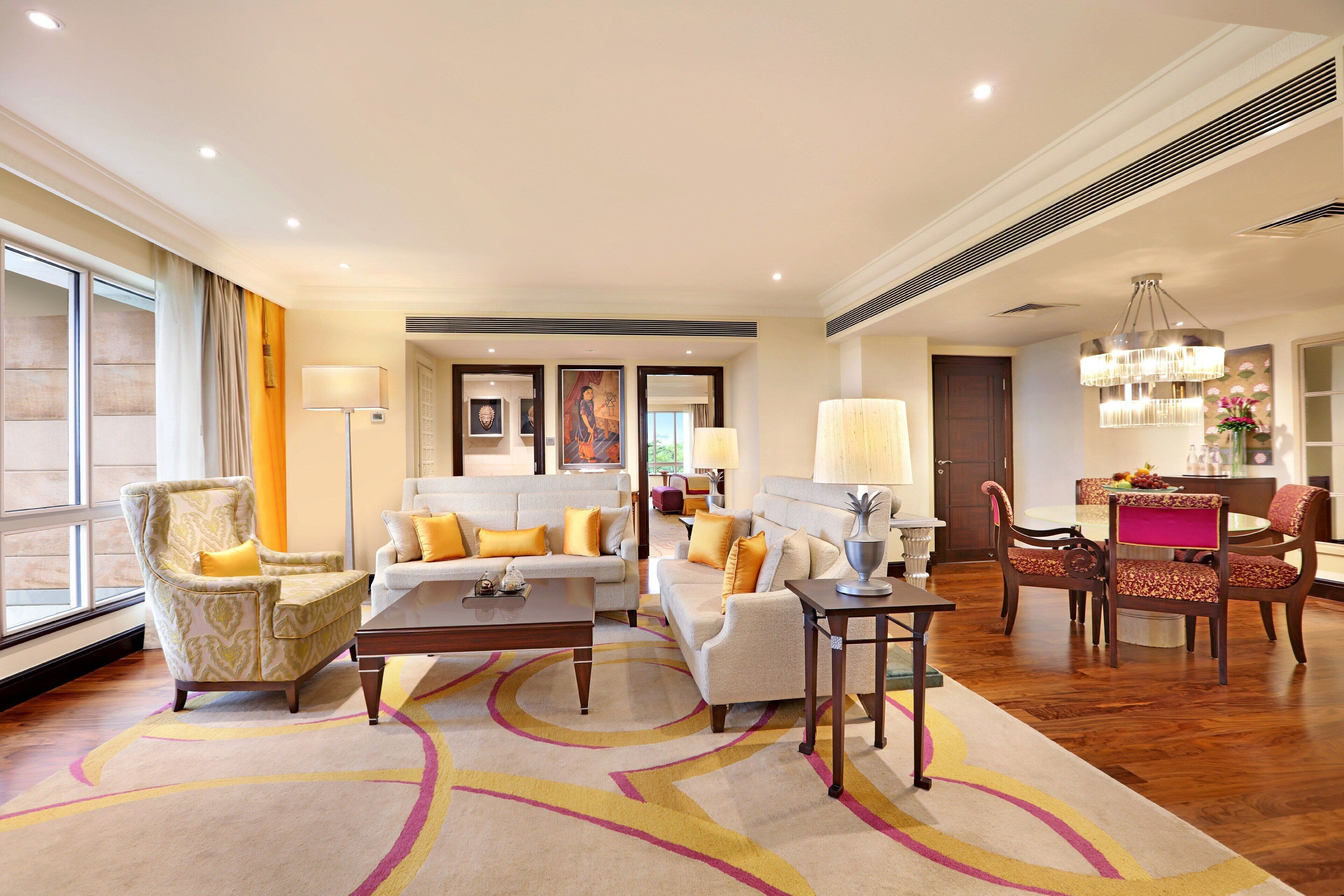 A spacious living room with a large window, a dining area, and a kitchen in the background.
