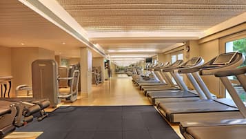 A gym with treadmills, weight machines, and a mirrored wall.