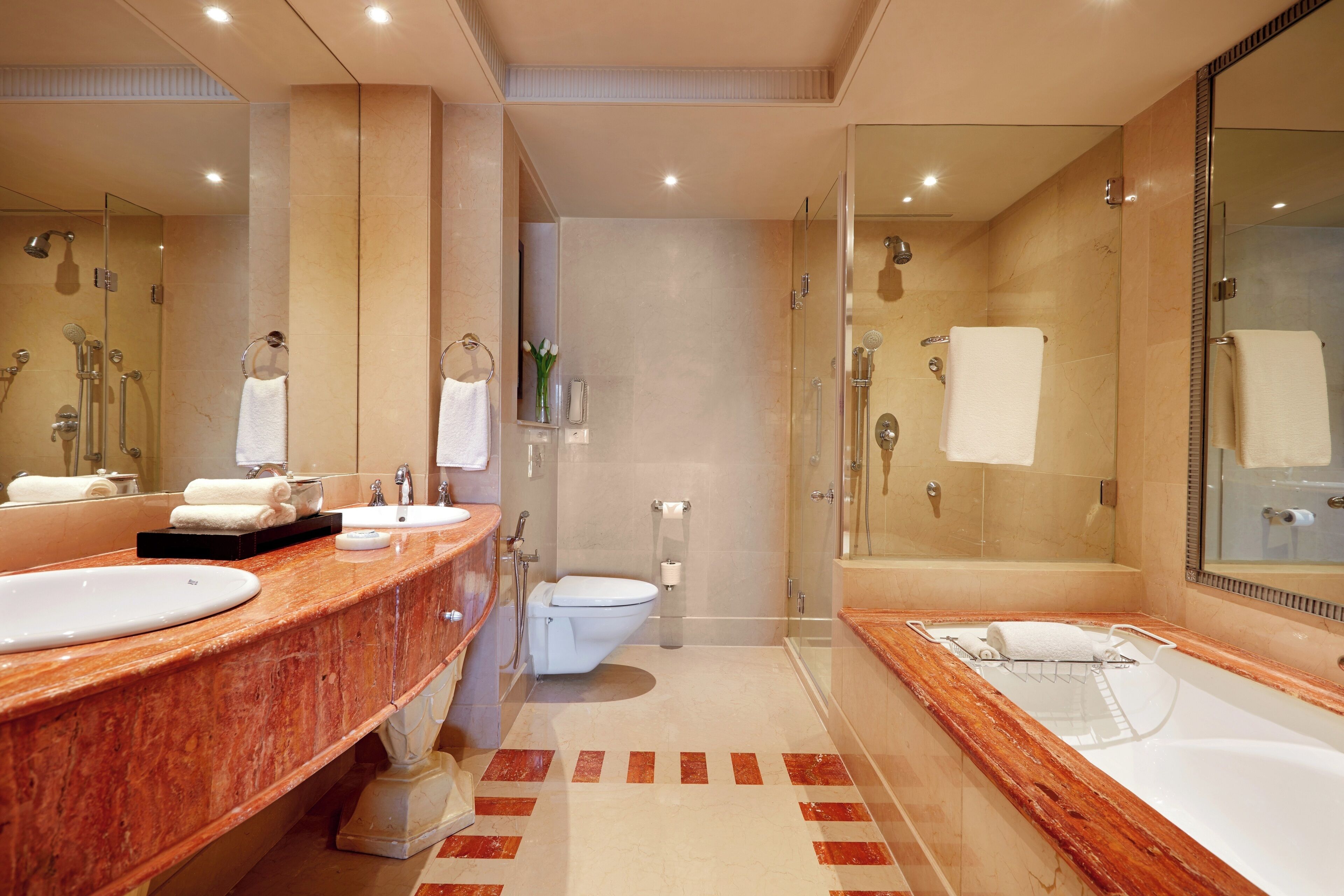 Un baño moderno con tocador de mármol, una bañera grande y cabina de ducha con paredes de vidrio.