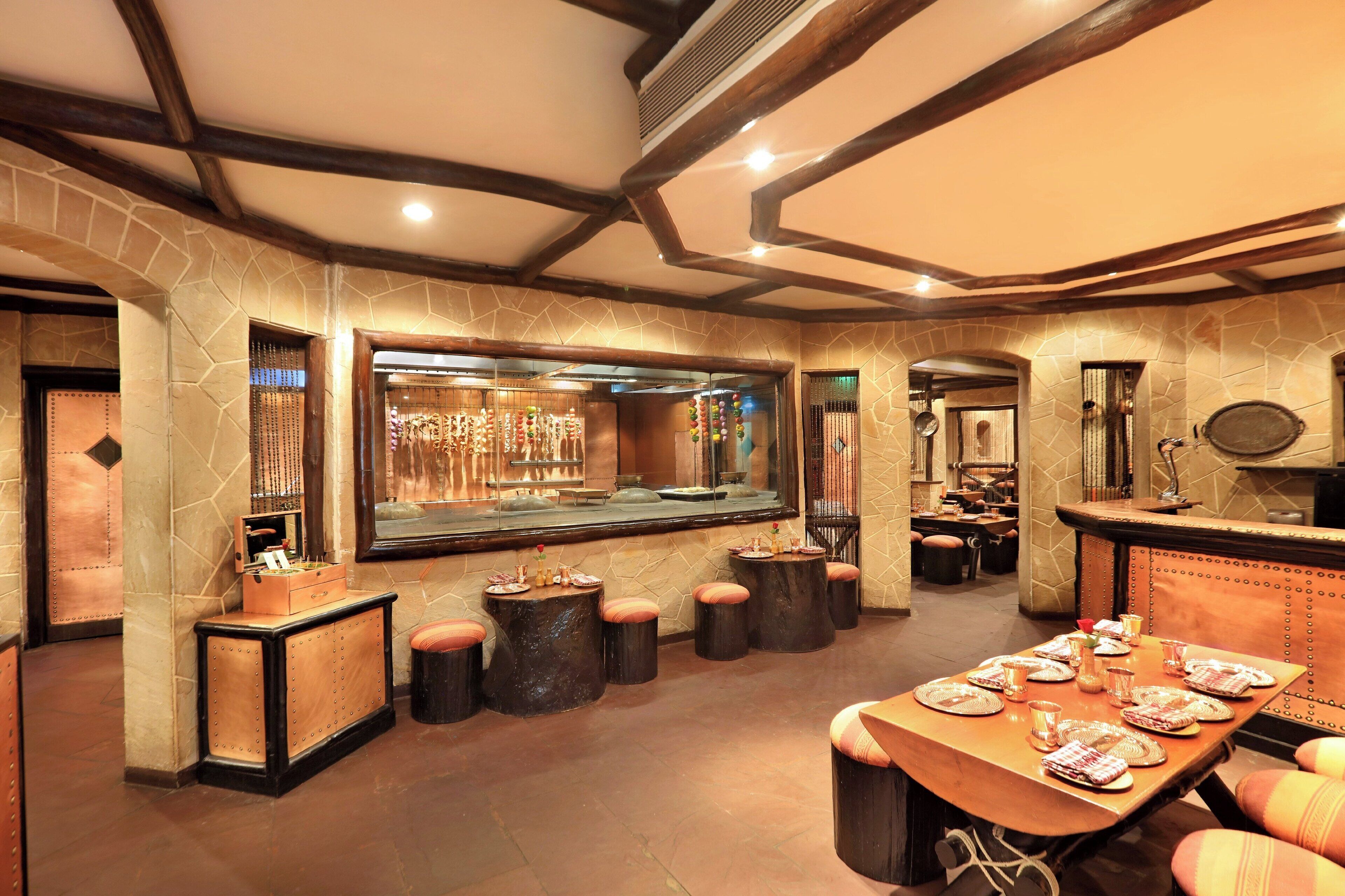 A restaurant with stone walls, wooden beams, and a long dining table set for a meal.