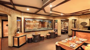 A restaurant with stone walls, wooden beams, and a long dining table set for a meal.