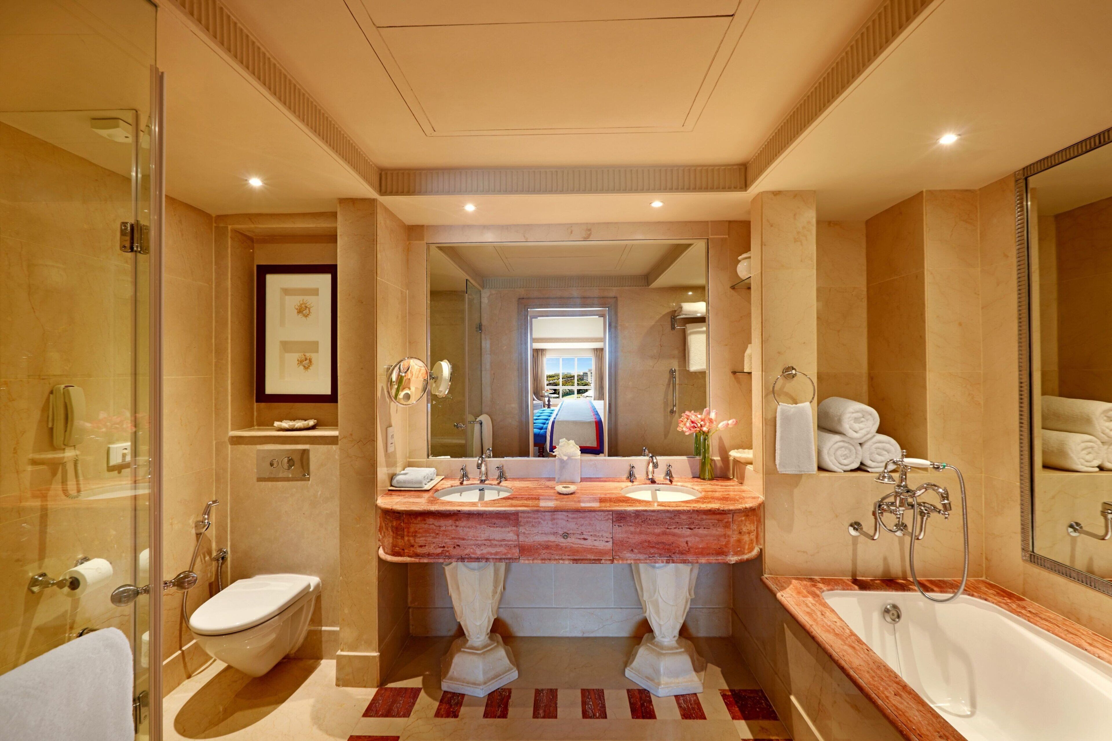 A modern bathroom with a large marble sink, a separate bathtub, and a glass-enclosed shower.