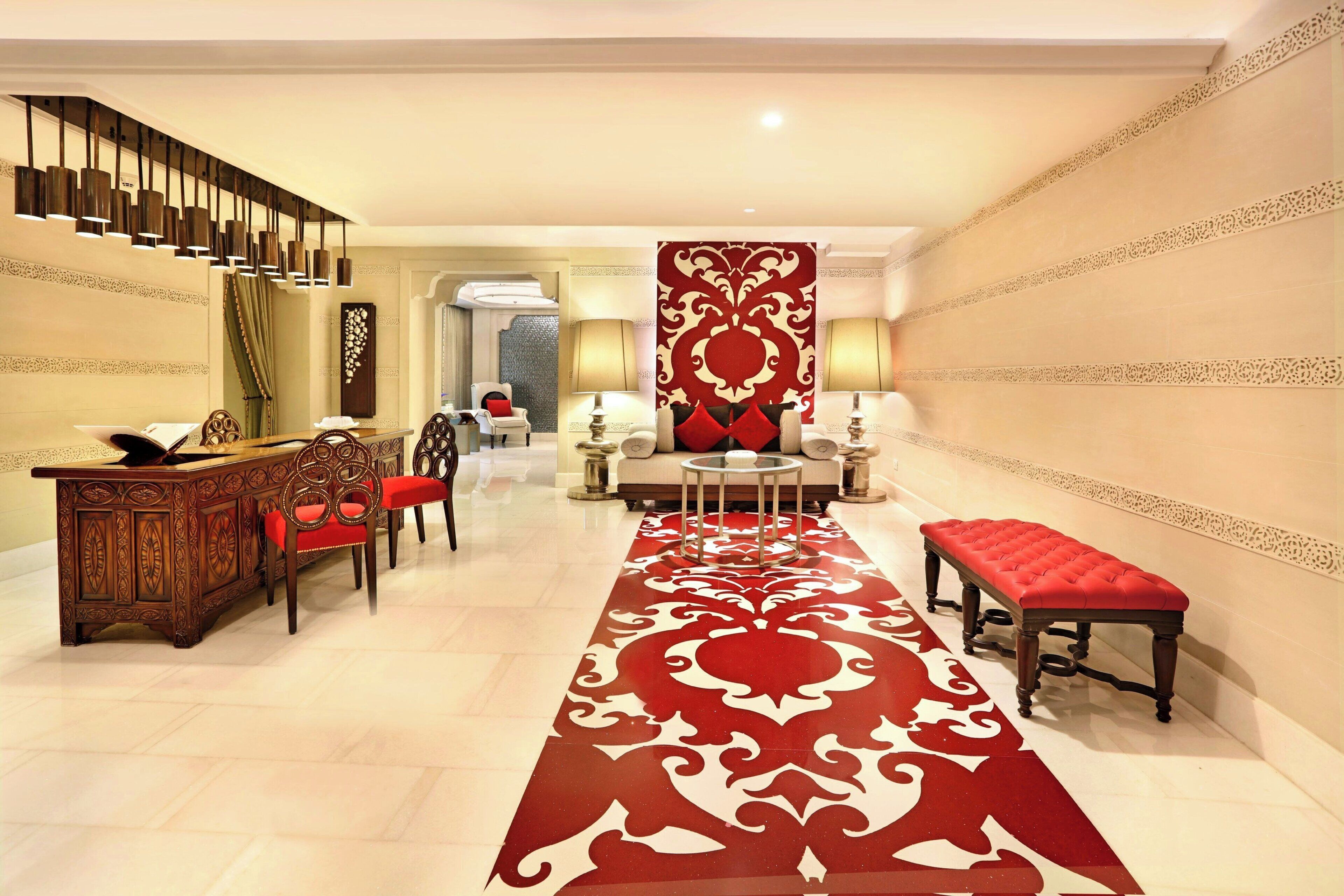 A hotel lobby with a red carpet, a reception desk, seating area, and a staircase.