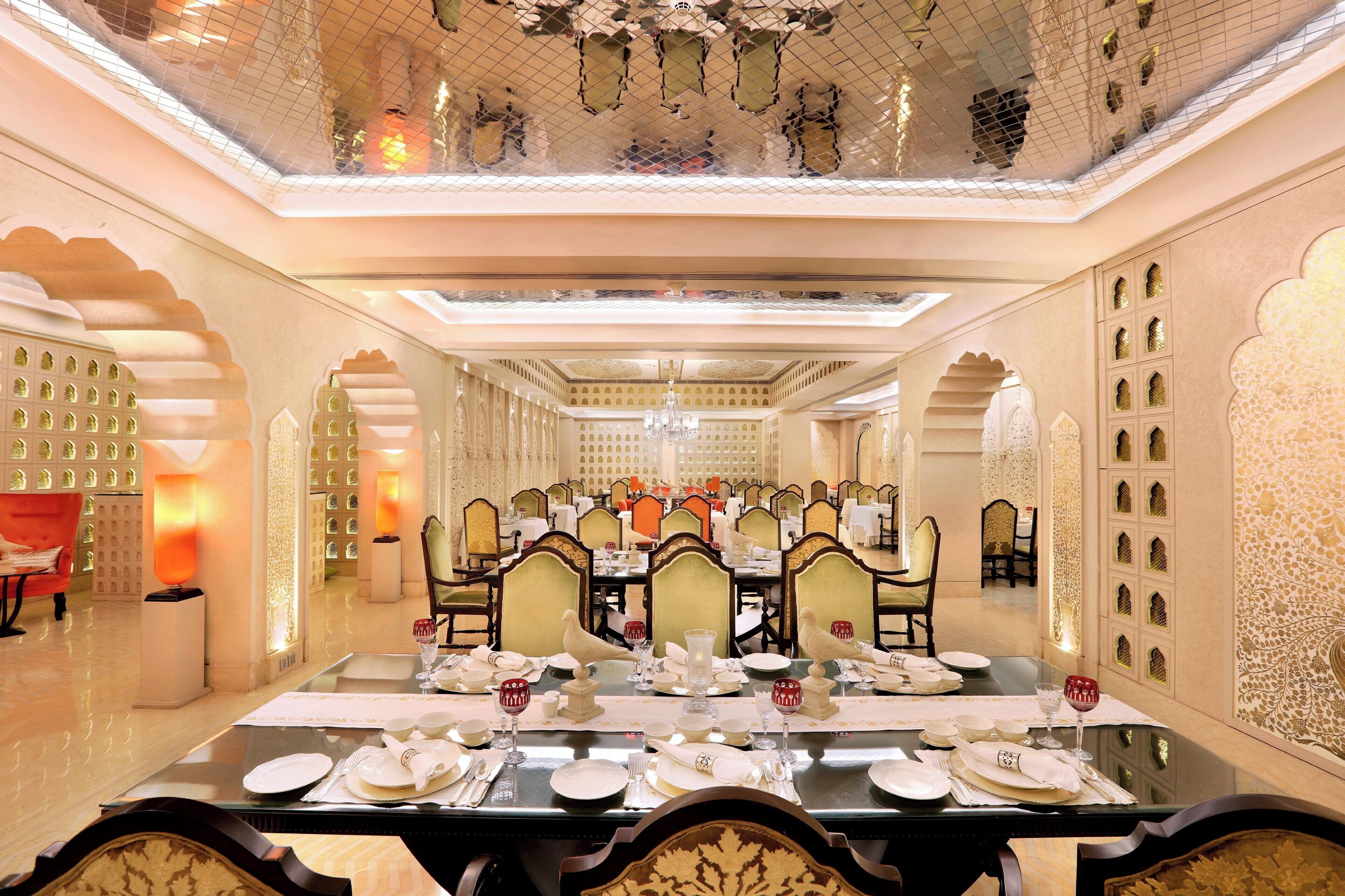 A dining area with a long table set for a meal, surrounded by ornate chairs and walls with intricate patterns.