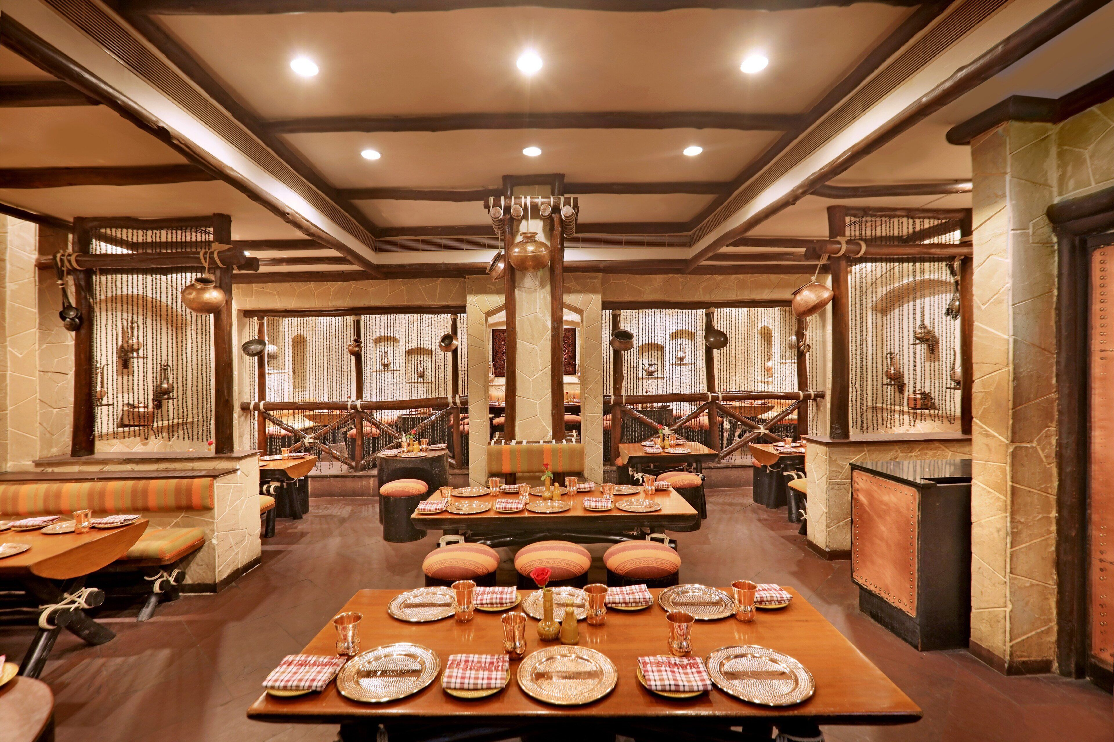 A restaurant with multiple tables set for dining, featuring a central column and hanging decorations.