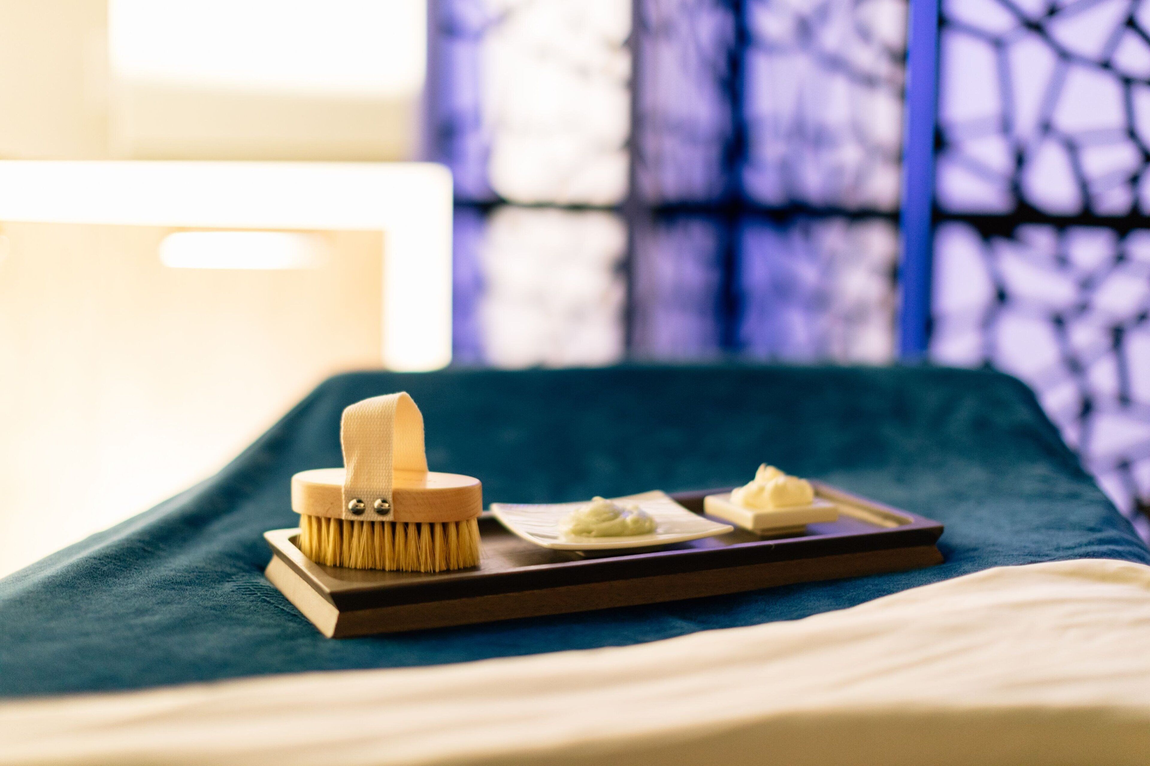 Une salle de bain bien rangée, avec une brosse en bois et un savon posés sur un plateau, une serviette et un flacon de lotion sur le comptoir.