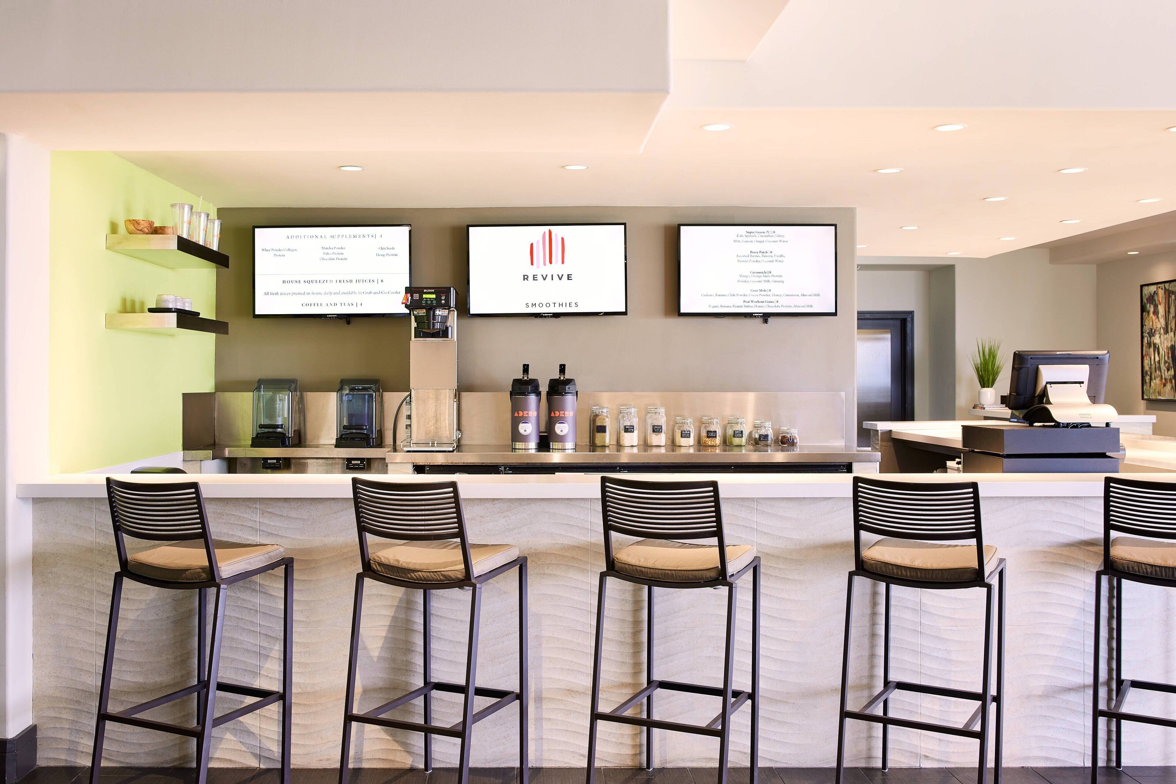 A modern bar area with a counter, bar stools, and a menu board.