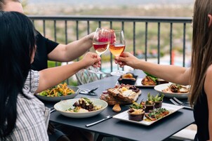 A dining table with various dishes and drinks, set outdoors with a railing in the background.