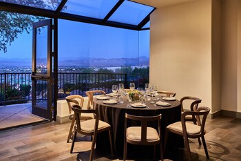 Enjoy a meal with a view of the city and mountains from this dining area with a round table and glass door leading to a balcony. at ADERO Scottsdale Resort, Autograph Collection