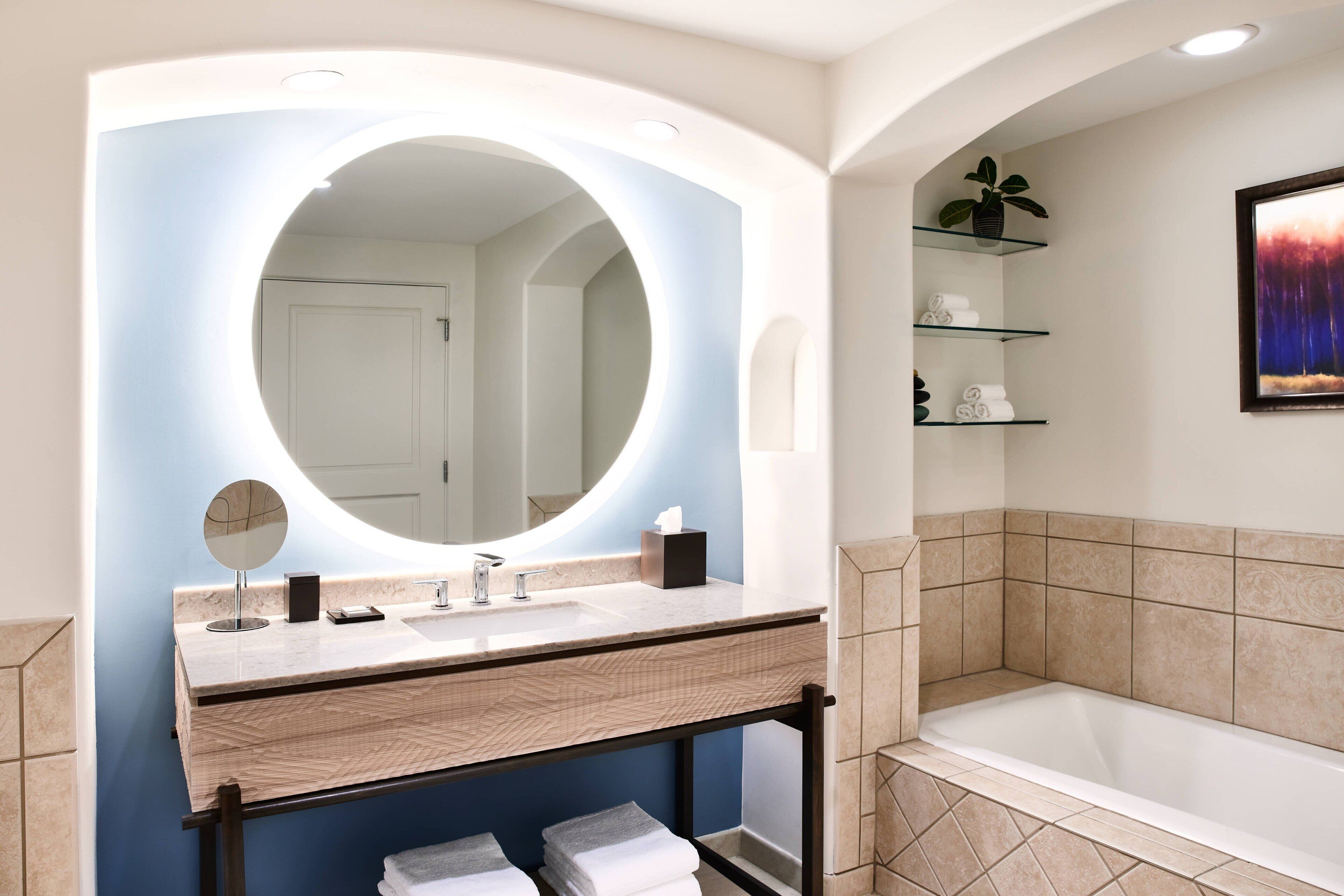 A modern bathroom with a large mirror, a sink, and a bathtub.