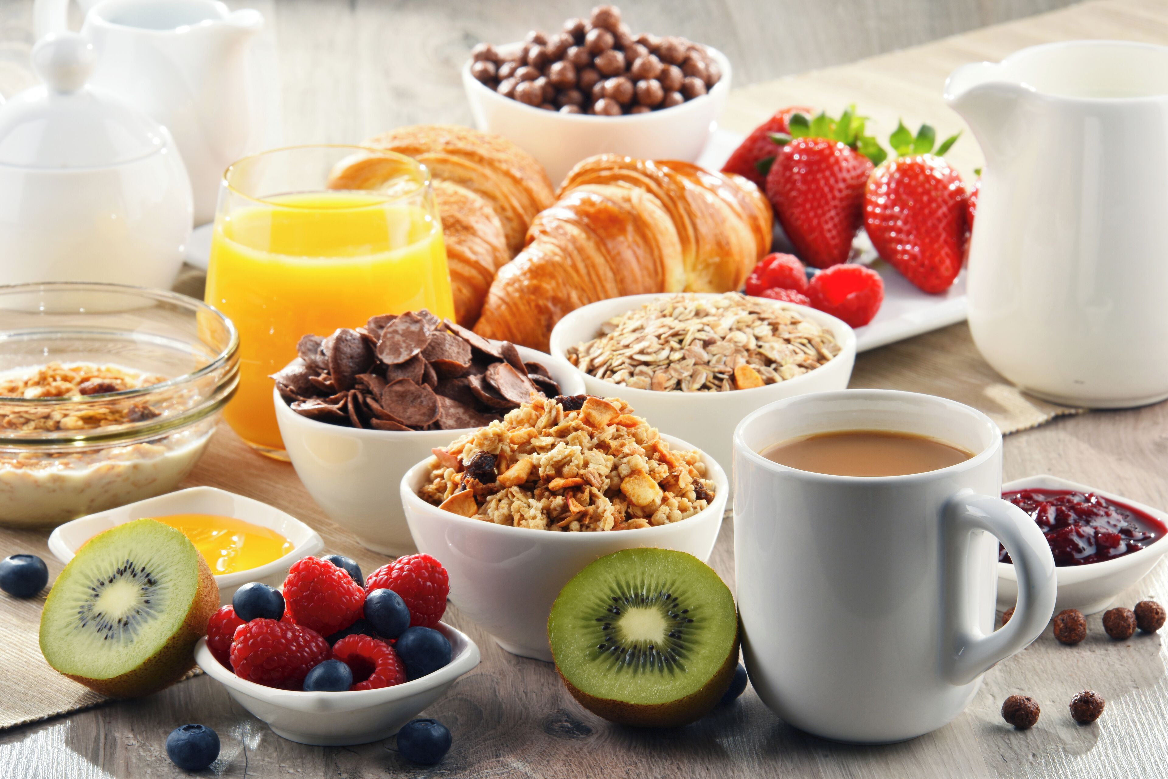 Ein Frühstückstisch mit Croissants, Erdbeeren, Blaubeeren und einem Glas Orangensaft.