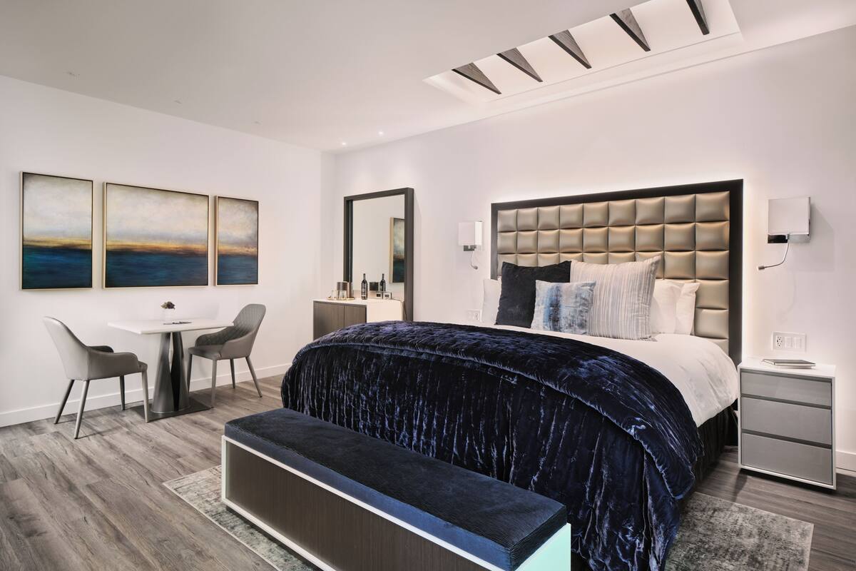 A modern bedroom with a large bed, a desk, and a chair.