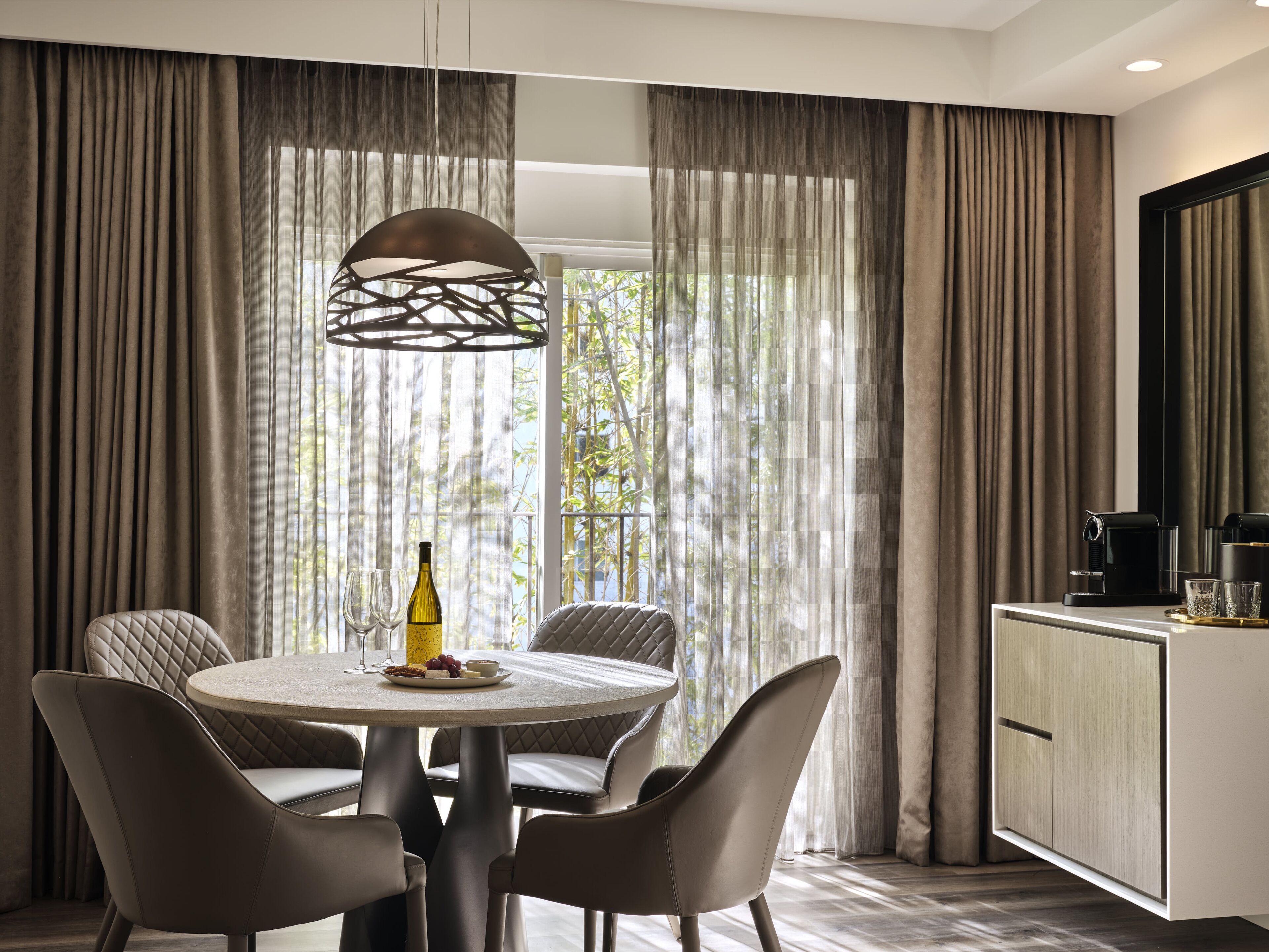 Un coin repas moderne avec une table ronde, quatre chaises, une bouteille de vin et des verres.