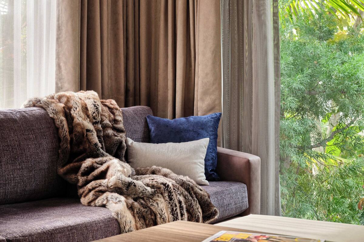 A living room with a sofa, a fur throw, and a window with curtains.