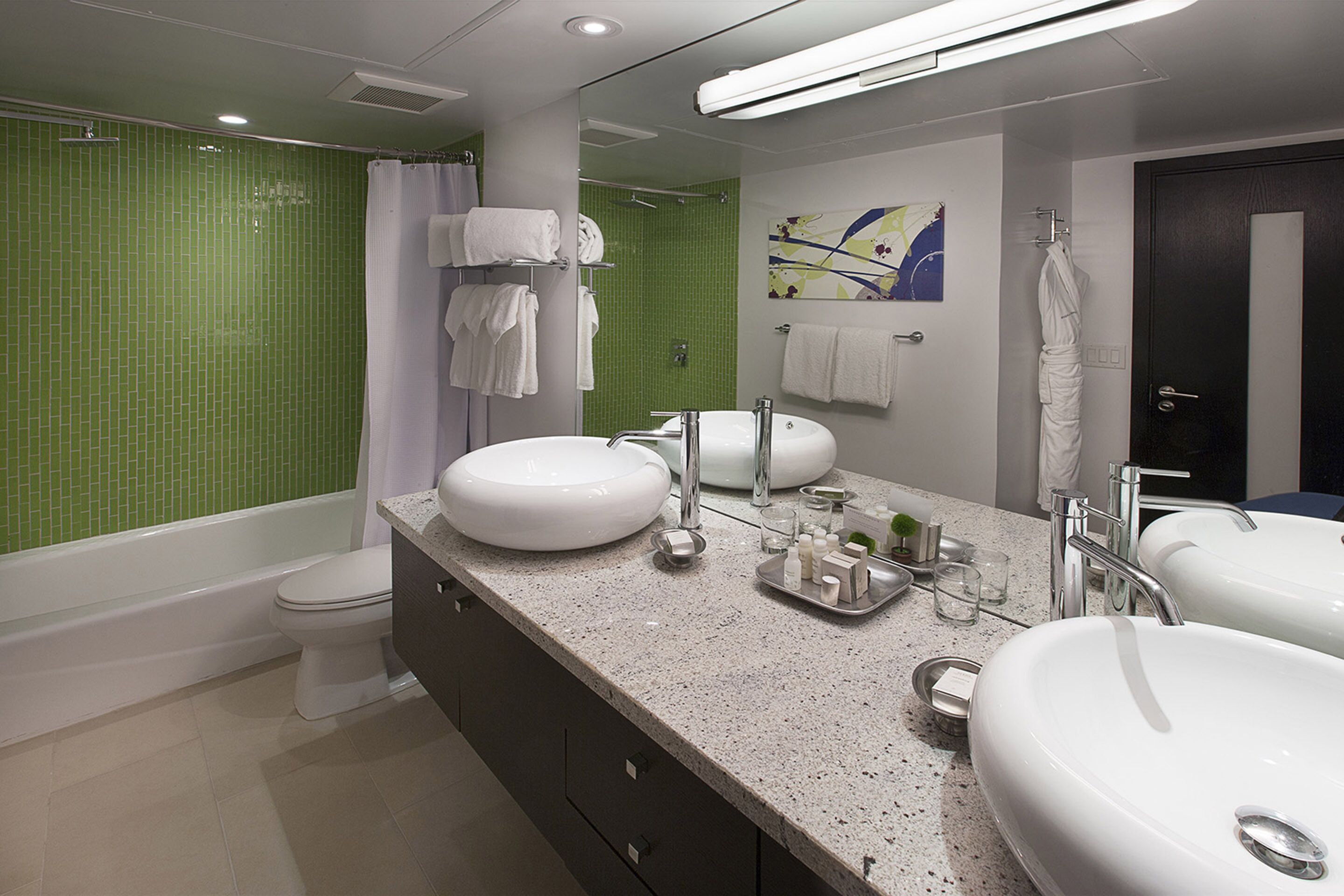 A modern bathroom with two sinks, a bathtub, and a toilet.