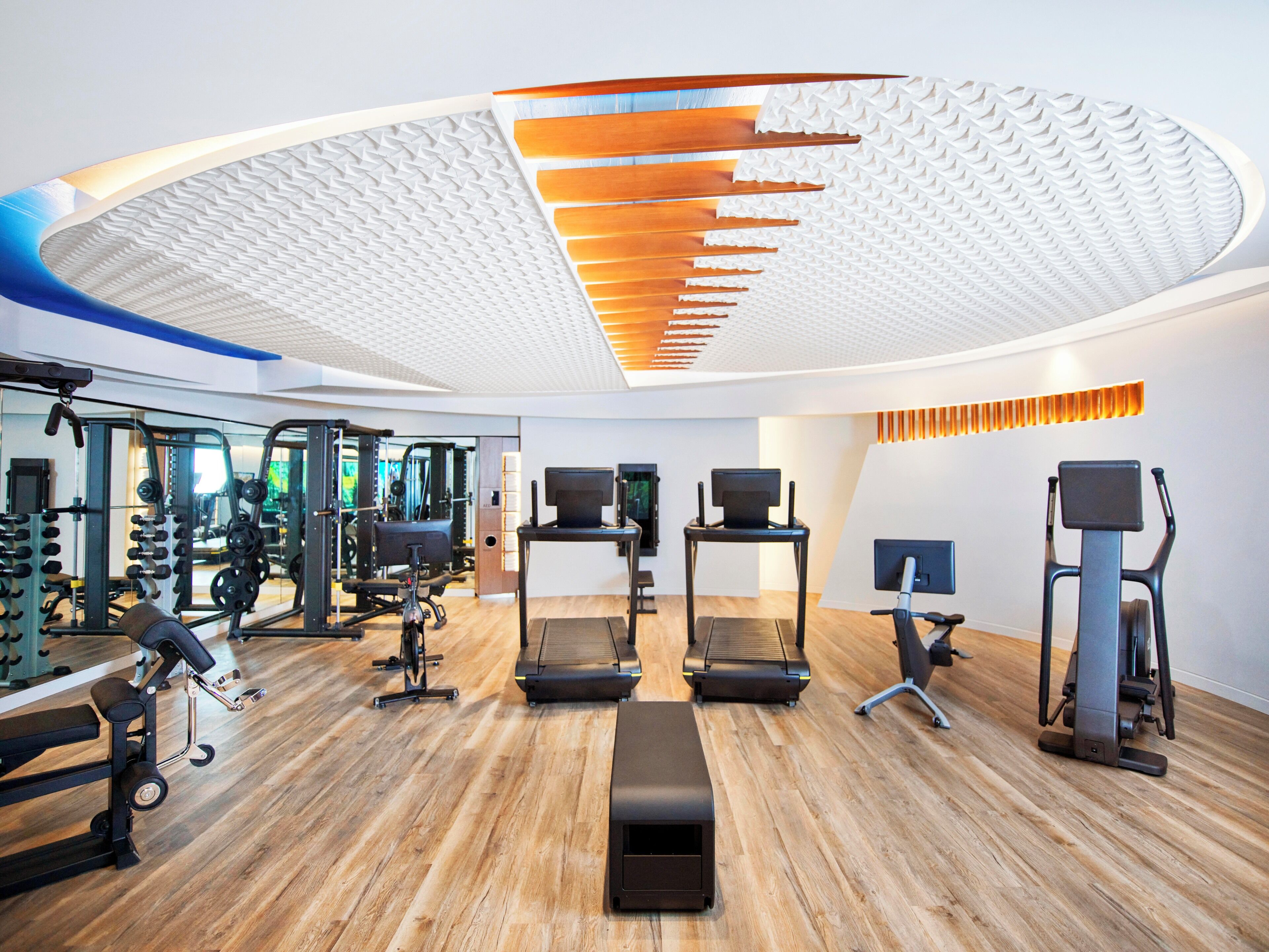 A modern gym with treadmills, elliptical machines, and weightlifting equipment.