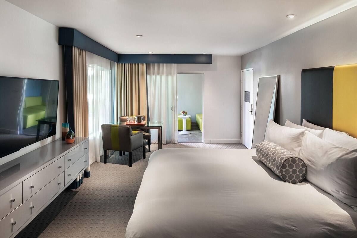 A hotel room with a bed, a TV, a desk, and a chair.
