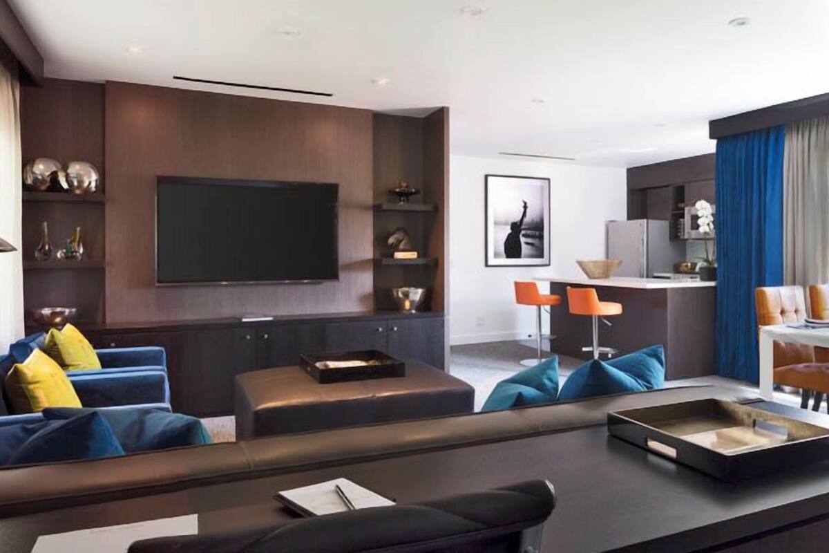 A modern living room with a flat-screen TV, a sofa, a coffee table, and a dining area with chairs and a table.