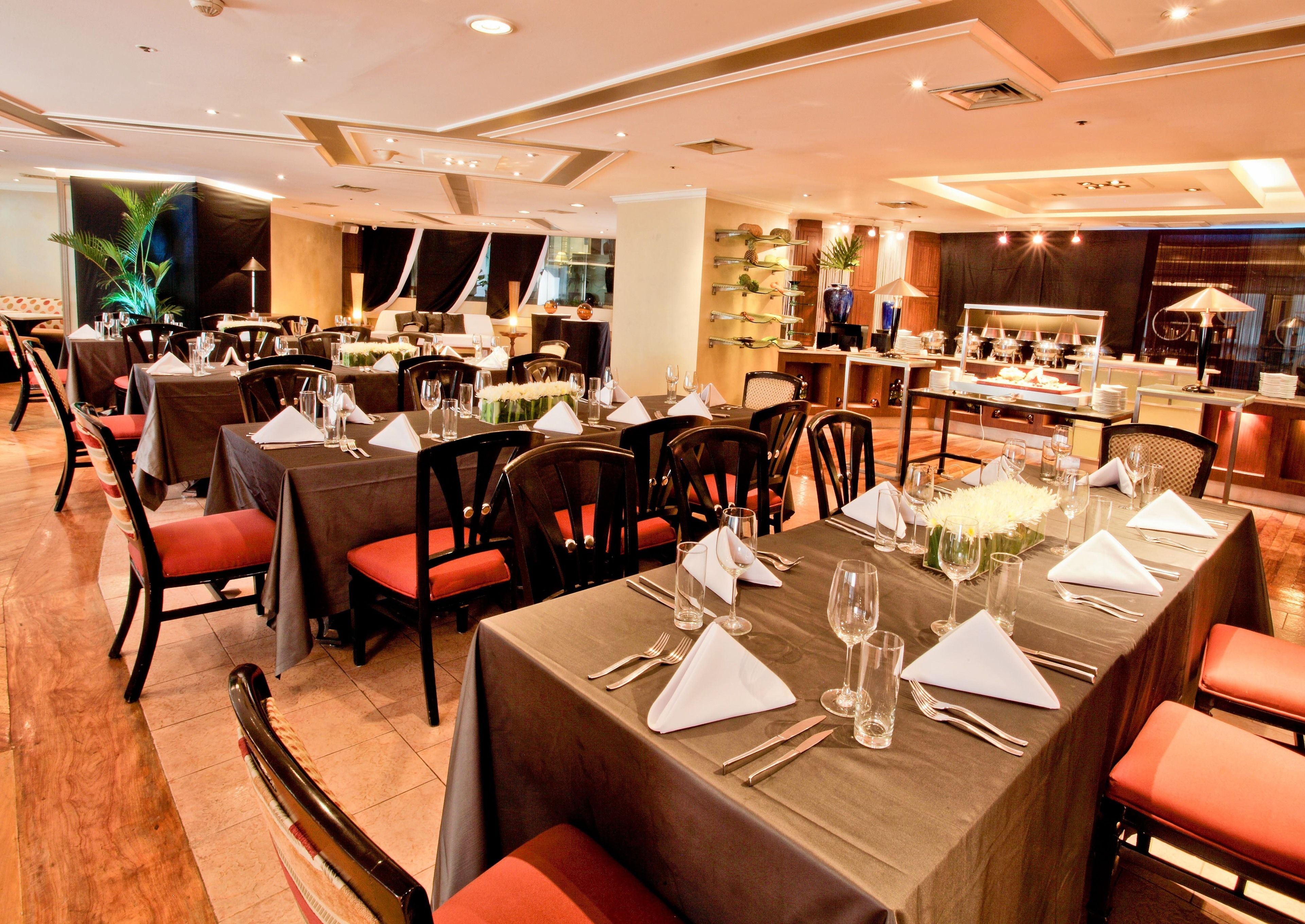 Ein Restaurant mit mehreren Esstischen, gedeckt mit weißen Servietten, Besteck und Weingläsern.