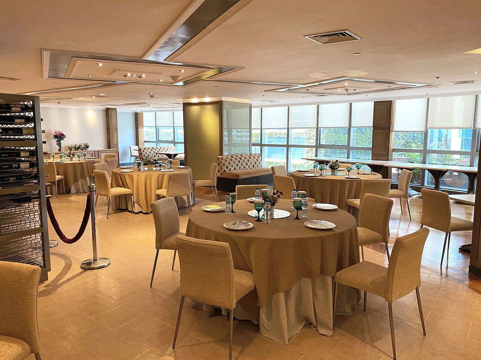 Un vaste espace dédié à la salle à manger, avec des tables rondes, des chaises et un meuble à vin.