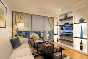Una sala de estar moderna con un sofá, un sillón, una mesa de centro y un televisor de pantalla plana montado en la pared.
