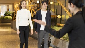 Eine moderne Hotellobby mit einer Treppe, einem Empfangsbereich und einer Sitzecke mit Pflanzen.