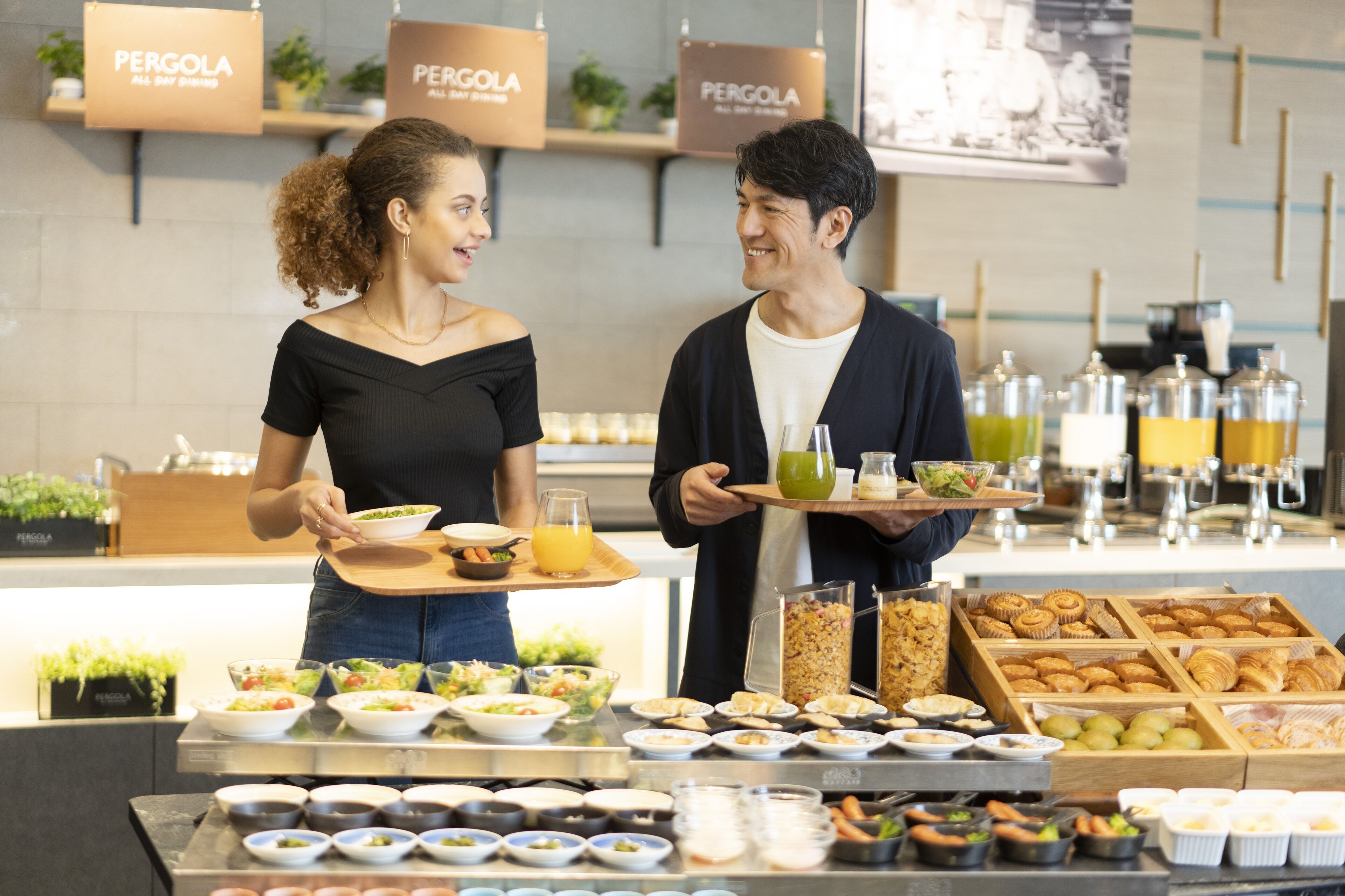 A buffet setup with various food items and drinks, including salads, fruits, and pastries.