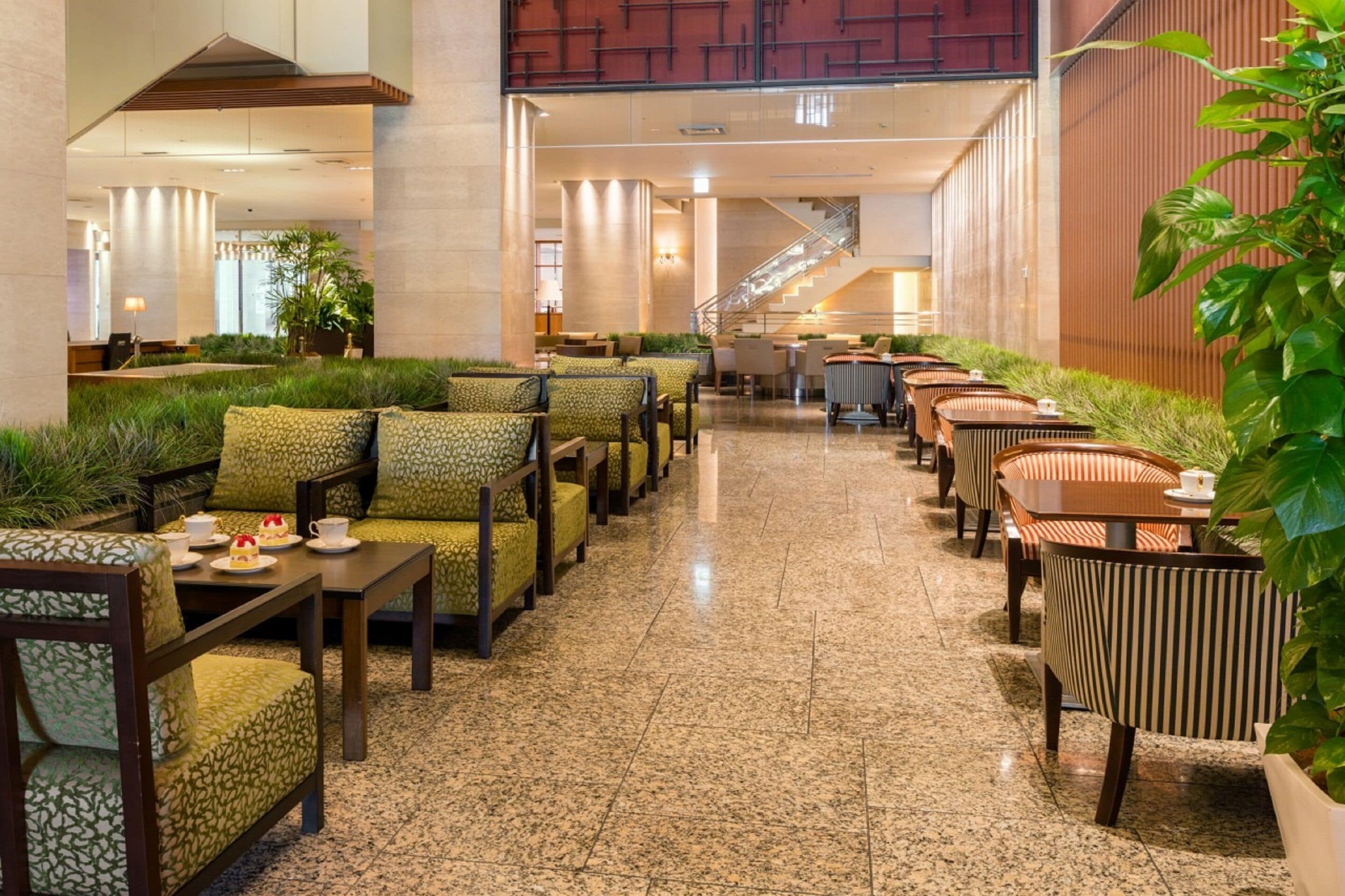 A spacious indoor seating area with multiple tables and chairs, a staircase, and a large potted plant.