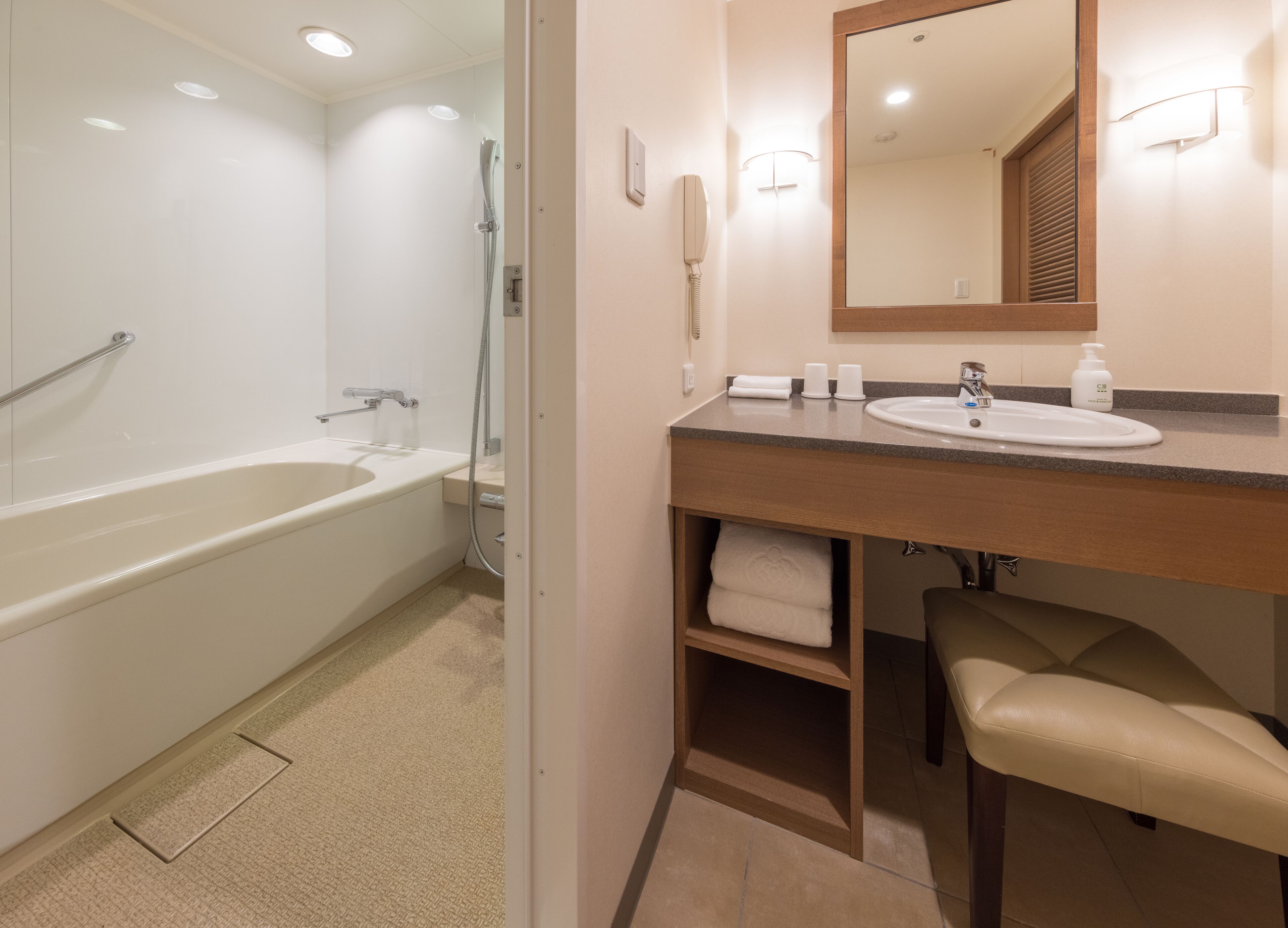 A modern bathroom with a bathtub, a sink, a mirror, and a towel rack.