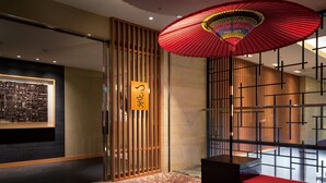 Een traditioneel Japans interieur met een tatami vloer, een rode paraplu aan het plafond en een houten schuifdeur met een bordje.