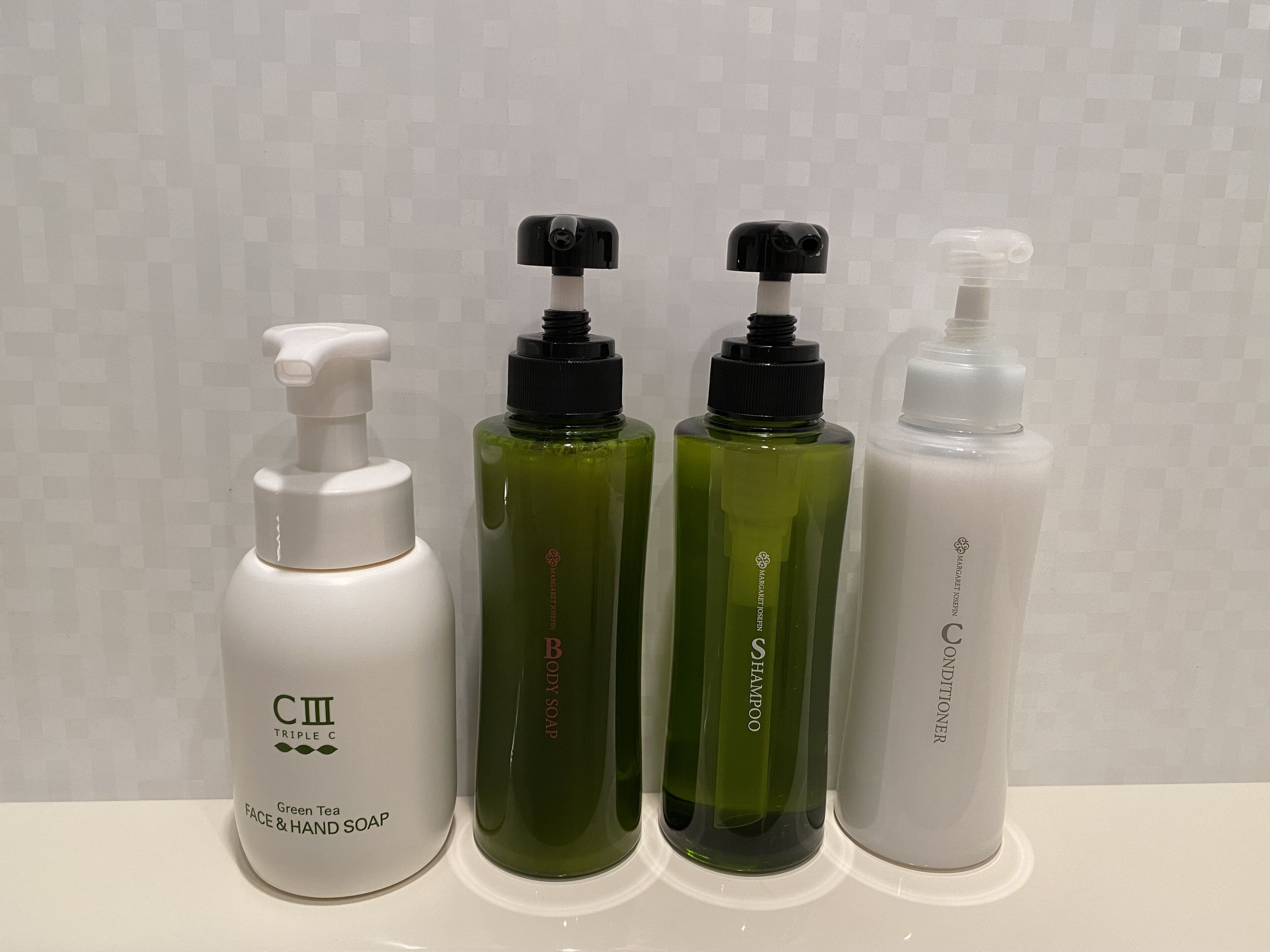 Four bottles of personal care products on a white surface.