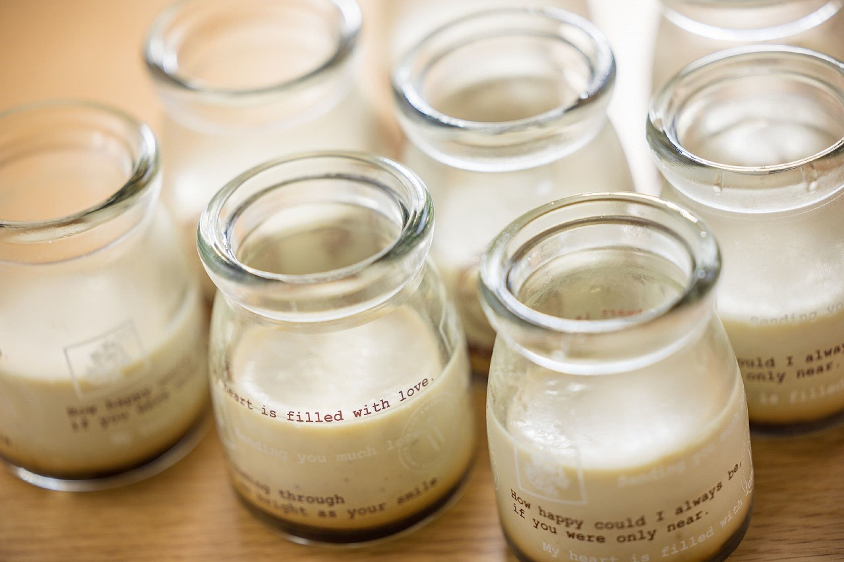 Several glass jars with a creamy substance and inspirational quotes on them.