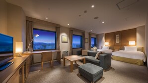 Ein Hotelzimmer mit Schreibtisch, einer Couch, einem Bett und einem Fernseher.