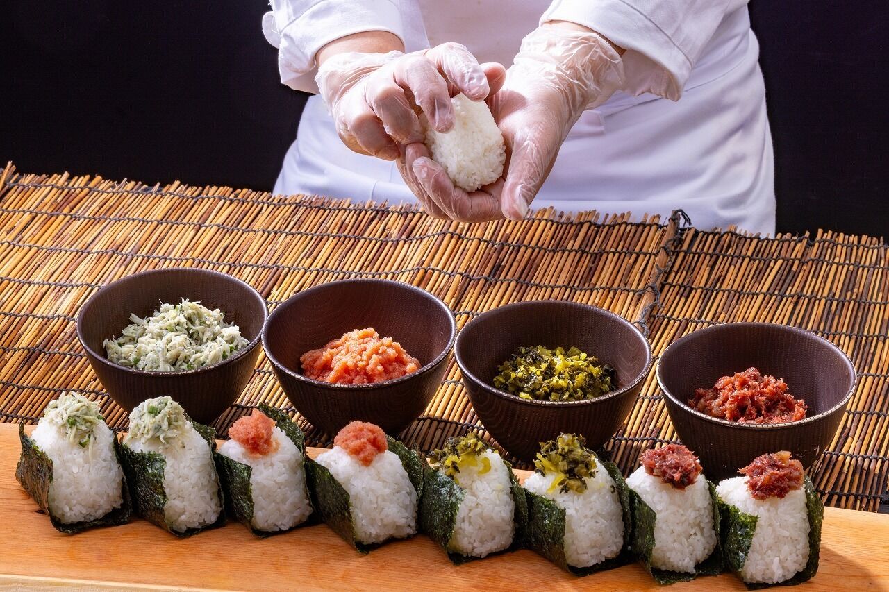 A person preparing sushi with various toppings in front of them.