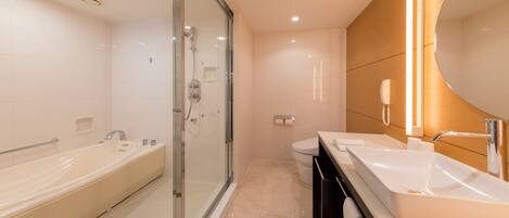 A modern bathroom with a glass-enclosed shower, a large bathtub, and a vanity with a mirror.