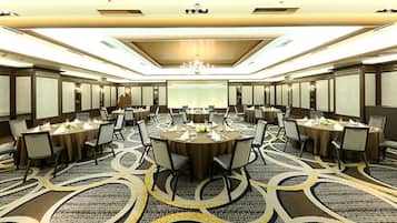 A conference room with multiple tables and chairs, a chandelier, and a patterned carpet.