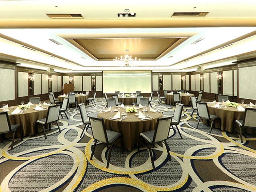 A conference room with multiple tables and chairs, a chandelier, and a patterned carpet.