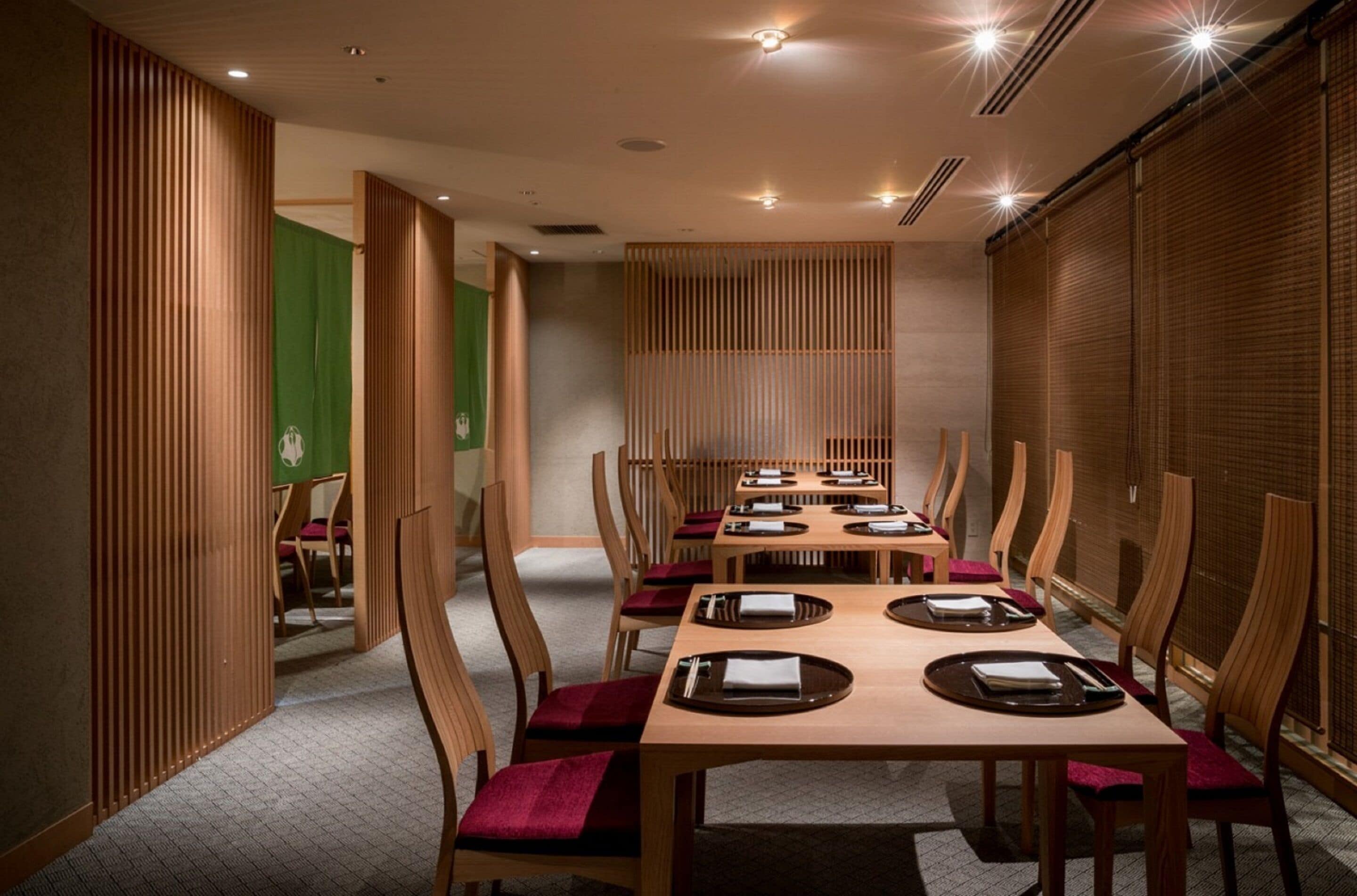 A restaurant with wooden tables and chairs, a green wall, and a wooden partition.