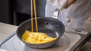 A person cooking an omelette in a non-stick pan on a kitchen stove.