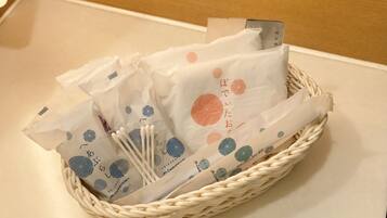 A woven basket containing several white paper bags with blue and orange geometric patterns and Japanese text, placed on a beige surface.